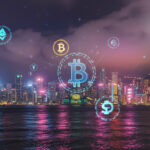 香港のビクトリアハーバーの夜景に仮想通貨シンボルを重ねた画像。仮想通貨ハブとしての成長を象徴。