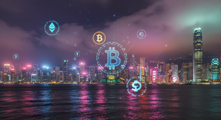 香港のビクトリアハーバーの夜景に仮想通貨シンボルを重ねた画像。仮想通貨ハブとしての成長を象徴。