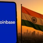 コインベースのロゴが表示されたスマートフォンとインド国旗が夕景の中に並ぶイメージ