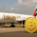 エミレーツ航空の旅客機とビットコインの象徴が並ぶ空港の風景