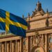 スウェーデン議会の建物と国旗を背景に、デジタルビットコインのモチーフを重ねたイメージ。国家ビットコイン準備金構想を象徴する写真。